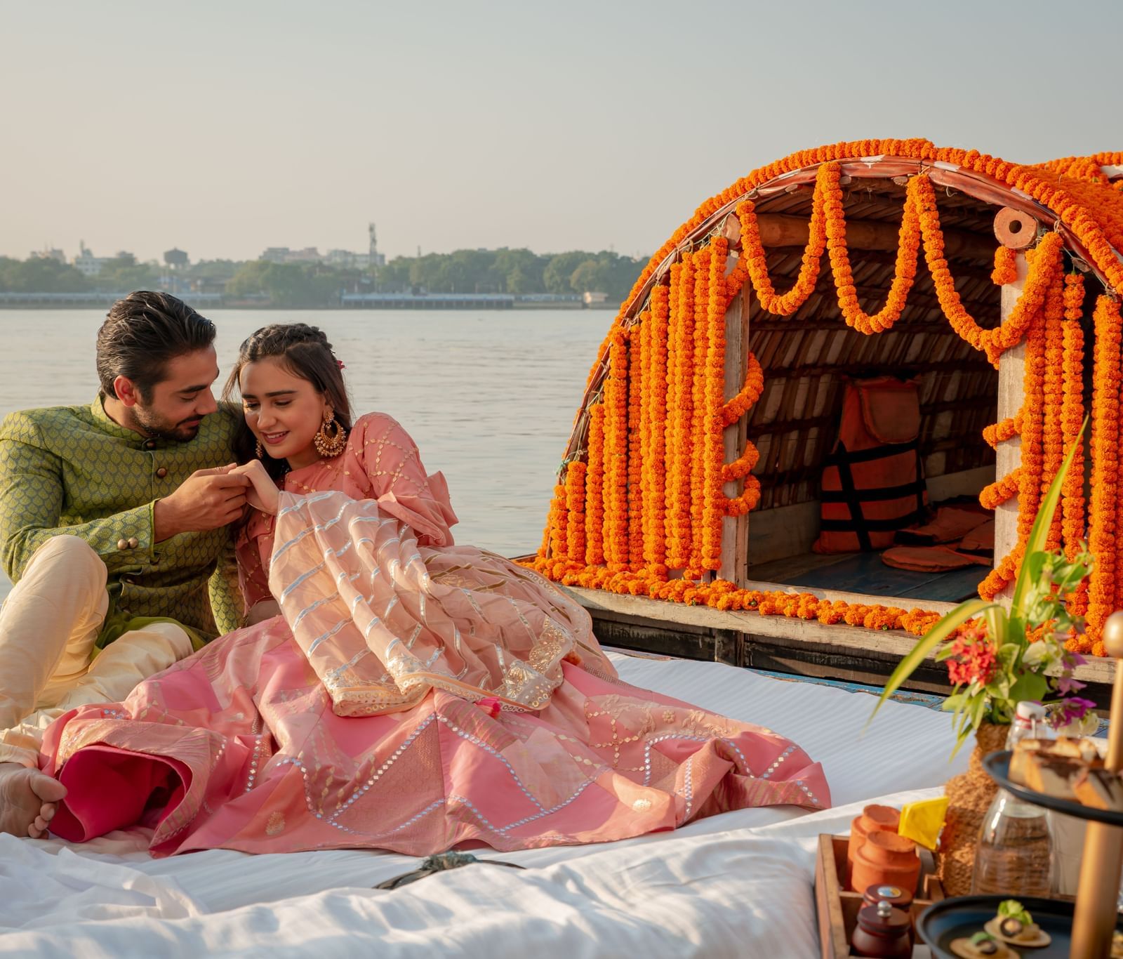 A couple in traditional attire enjoying a decorated riverside picnic on a Nauka (boat) - Polo Floatel Kolkata
