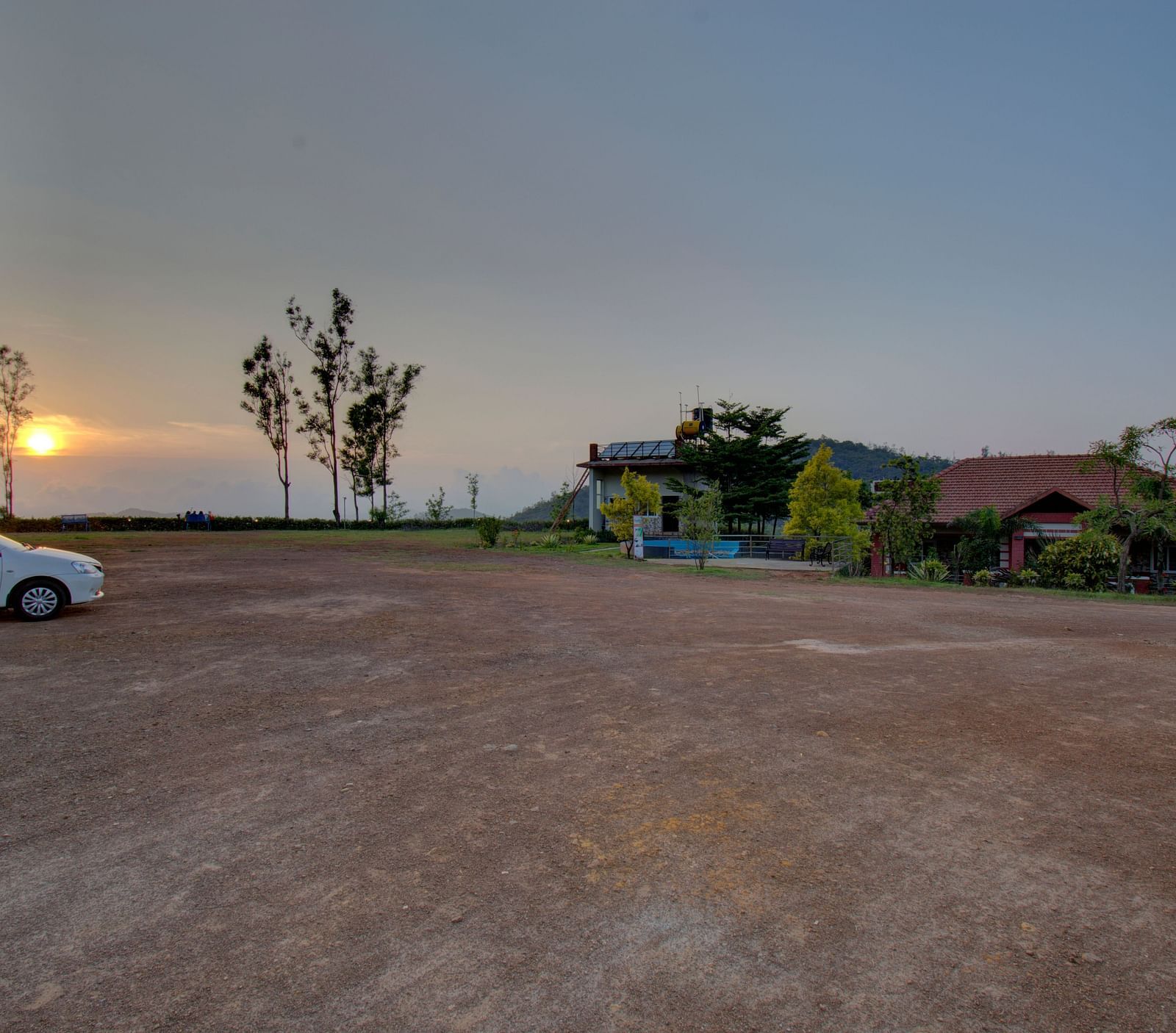 A car parked  on a tiled floor with a sunset view and greenery | Woodstock Resorts, Coorg
