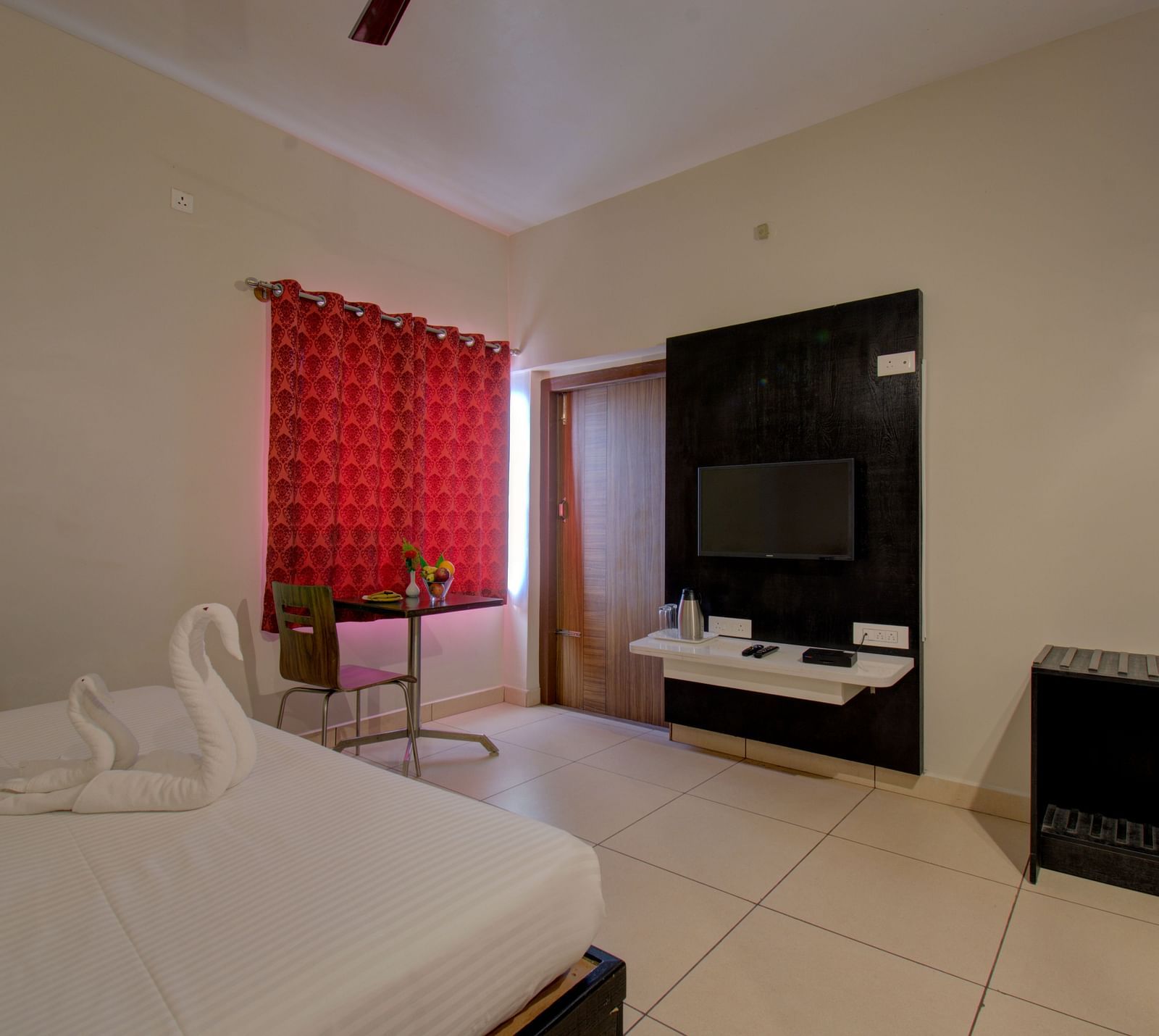 A bedroom with a bed, TV, curtained window, cabinet | Superior Room | Woodstock Resorts, Coorg