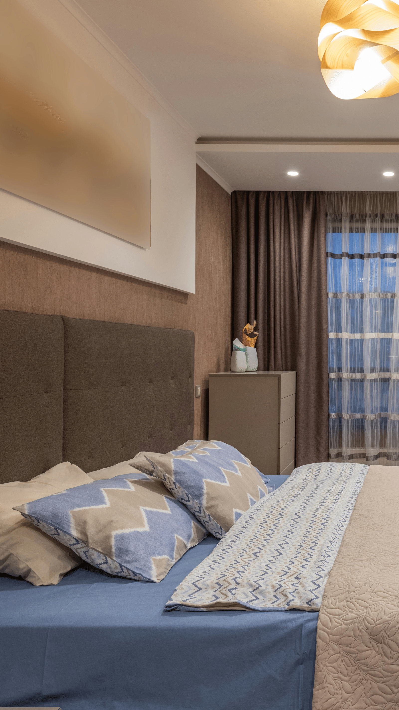 Cosy hotel room with large bed, soft lighting, modern decor, and a wall-mounted TV