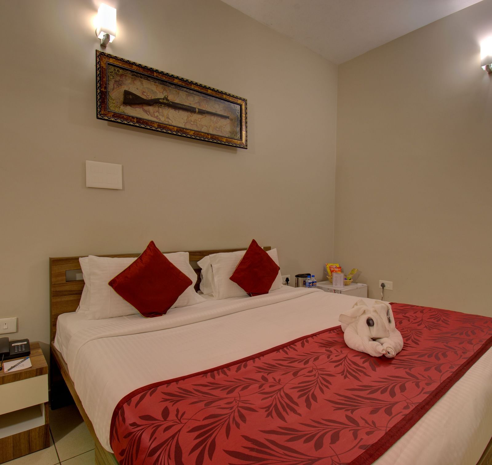 Bedroom with a huge bed, bedside table, and a decorative piece of a gun on the wall | Superior Room | Woodstock Resorts, Coorg