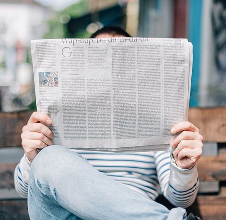 A hidden face behind a crisp newspaper, lost in morning reading