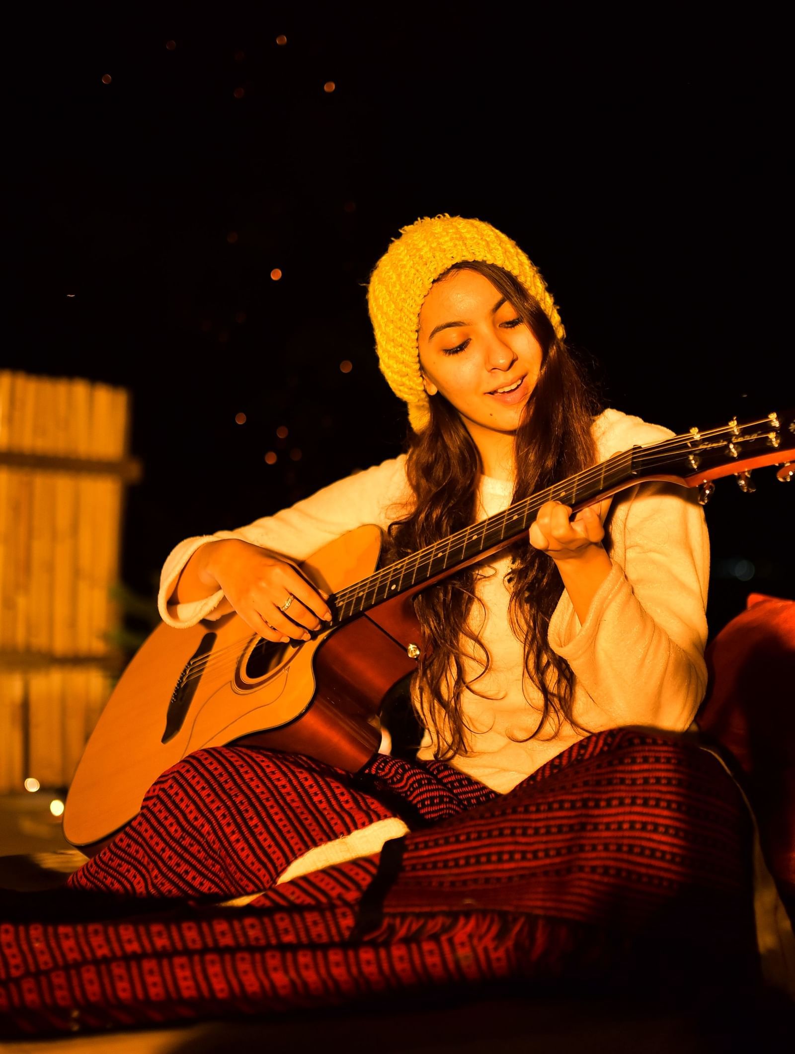 A guest playing guitar under warm evening lights in an open-air setup - Polo Resort Cherrapunjee