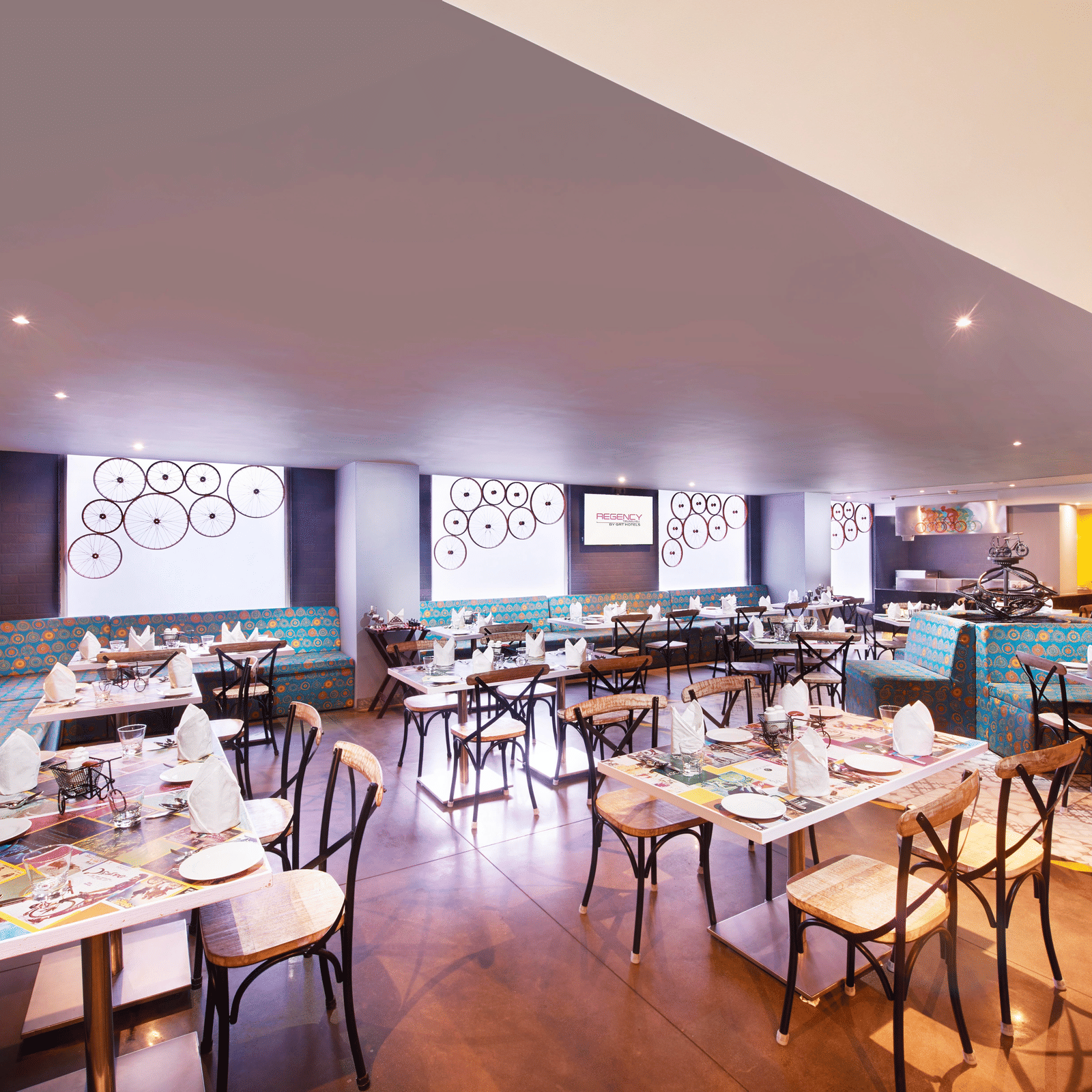 A brightly lit restaurant with chairs, a long bar counter, and a colourful wall mural | Regency Hotel near Tirunelveli Railway Station by GRT