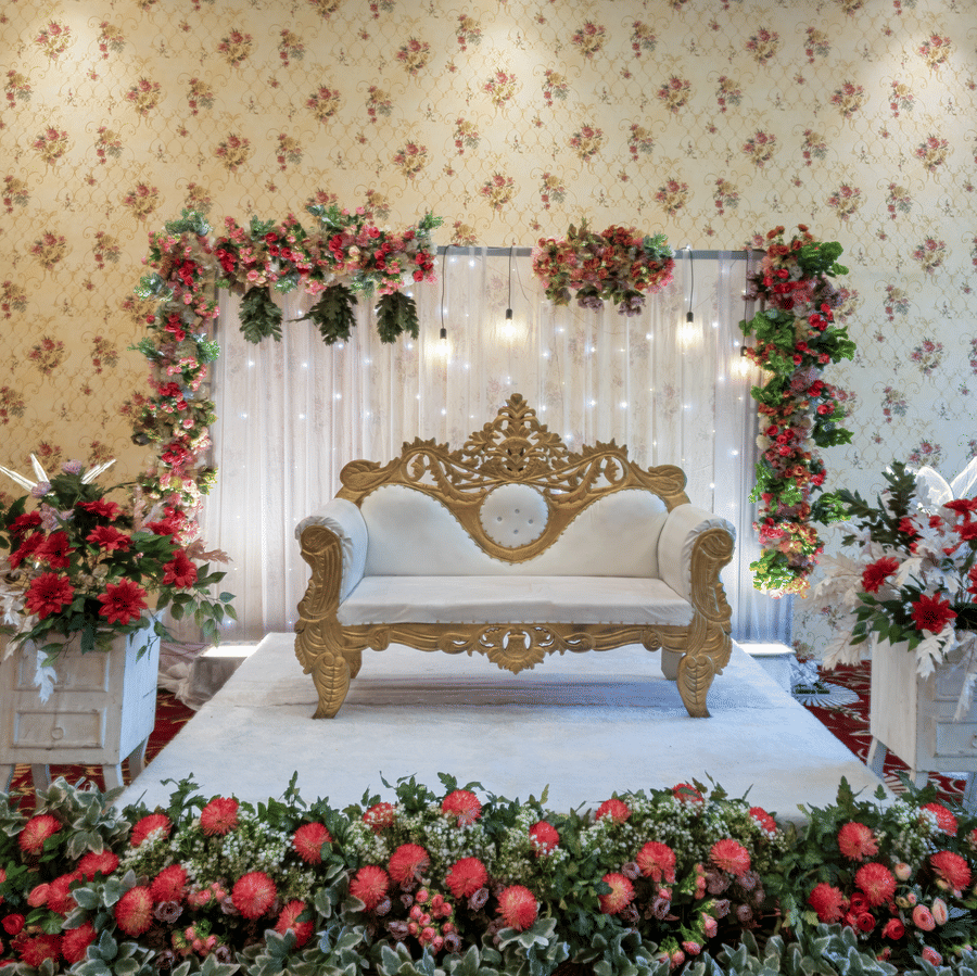 Wedding stage decorated with a floral arch and ornate seating at Mango Grove Hotel.