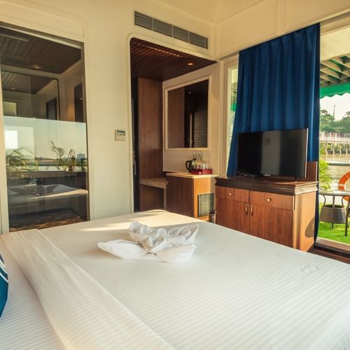 a well made bed with blue pillows and a tv opposite to it - polo floatel kolkata