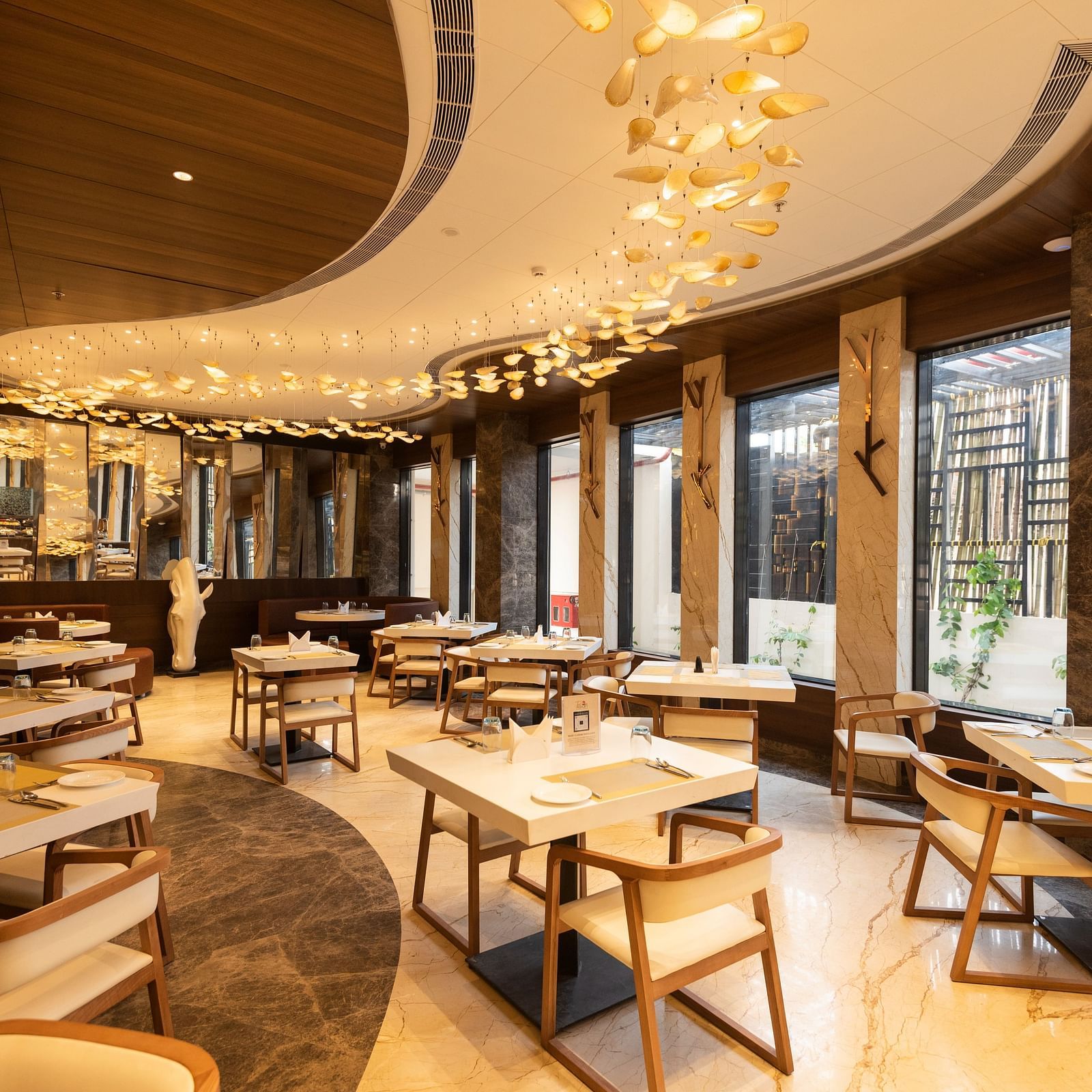 a warmly-lit interior of Tempt Asian Restaurant decked with elegant seating arrangements at Hotel Park Elanza, Coimbatore
