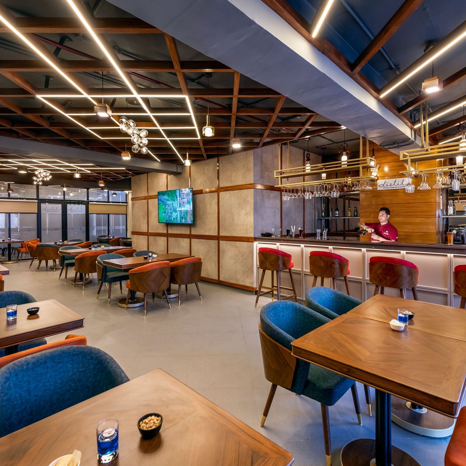 Interior of a Distil bar with wooden accents, blue chairs, and warm lighting labeled 'Distil Bar'