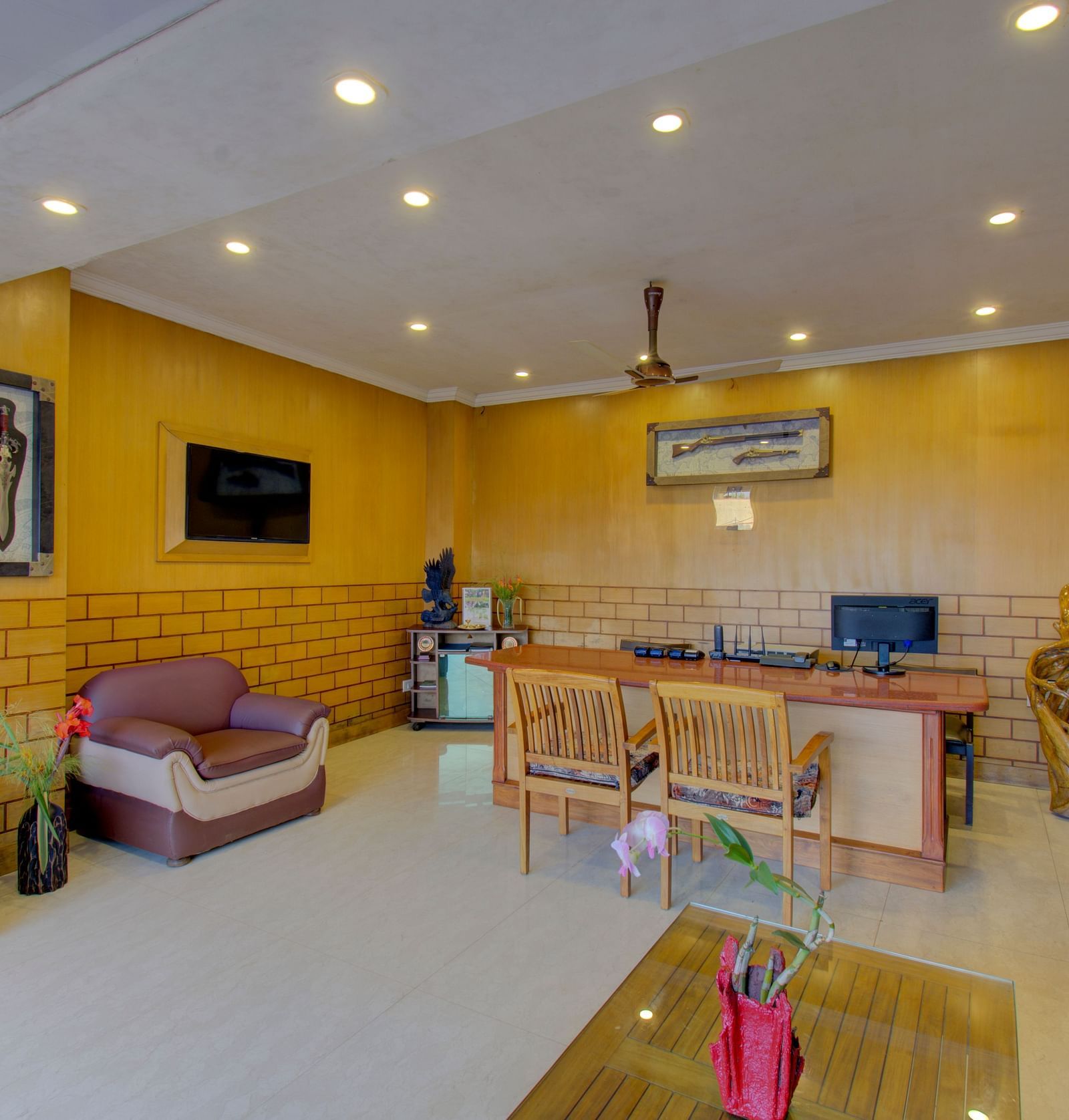A reception area showcasing a television and additional seating near the reception desk | Woodstock Resorts, Coorg