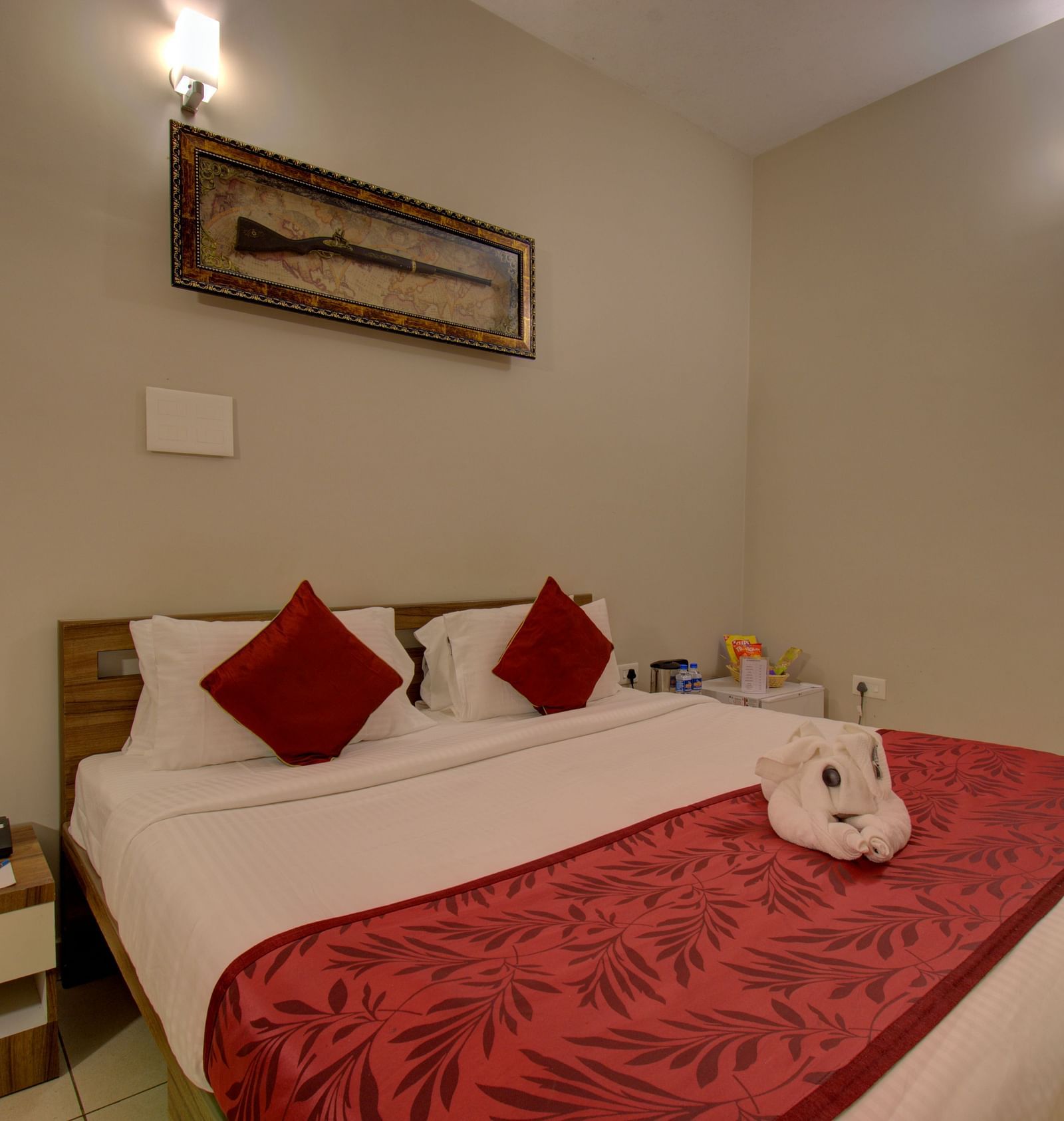 Bedroom with a huge bed, bedside table, and a decorative piece of a gun on the wall | Superior Room | Woodstock Resorts, Coorg