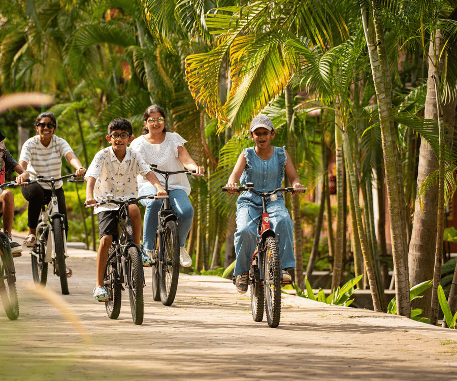 kids Cycling on a pathway next to coconut trees  - Ibex River Resort, Pollachi
