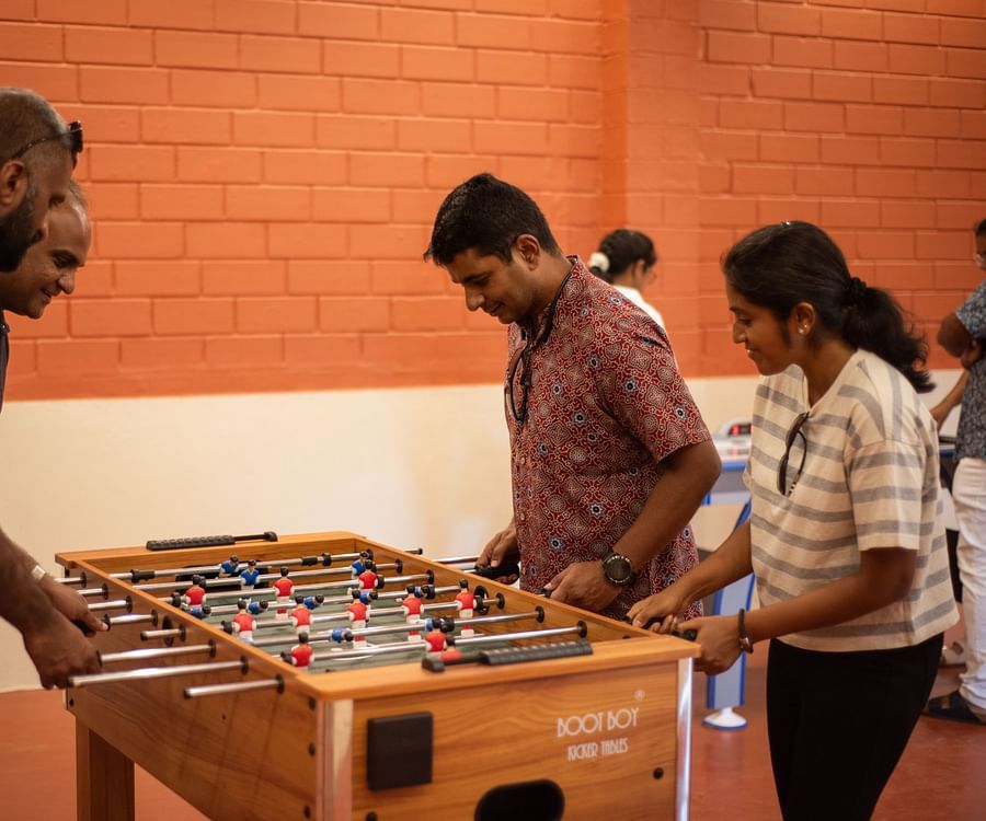 a group of people playing foosball inside the game room at Ibex River Resort, Pollachi