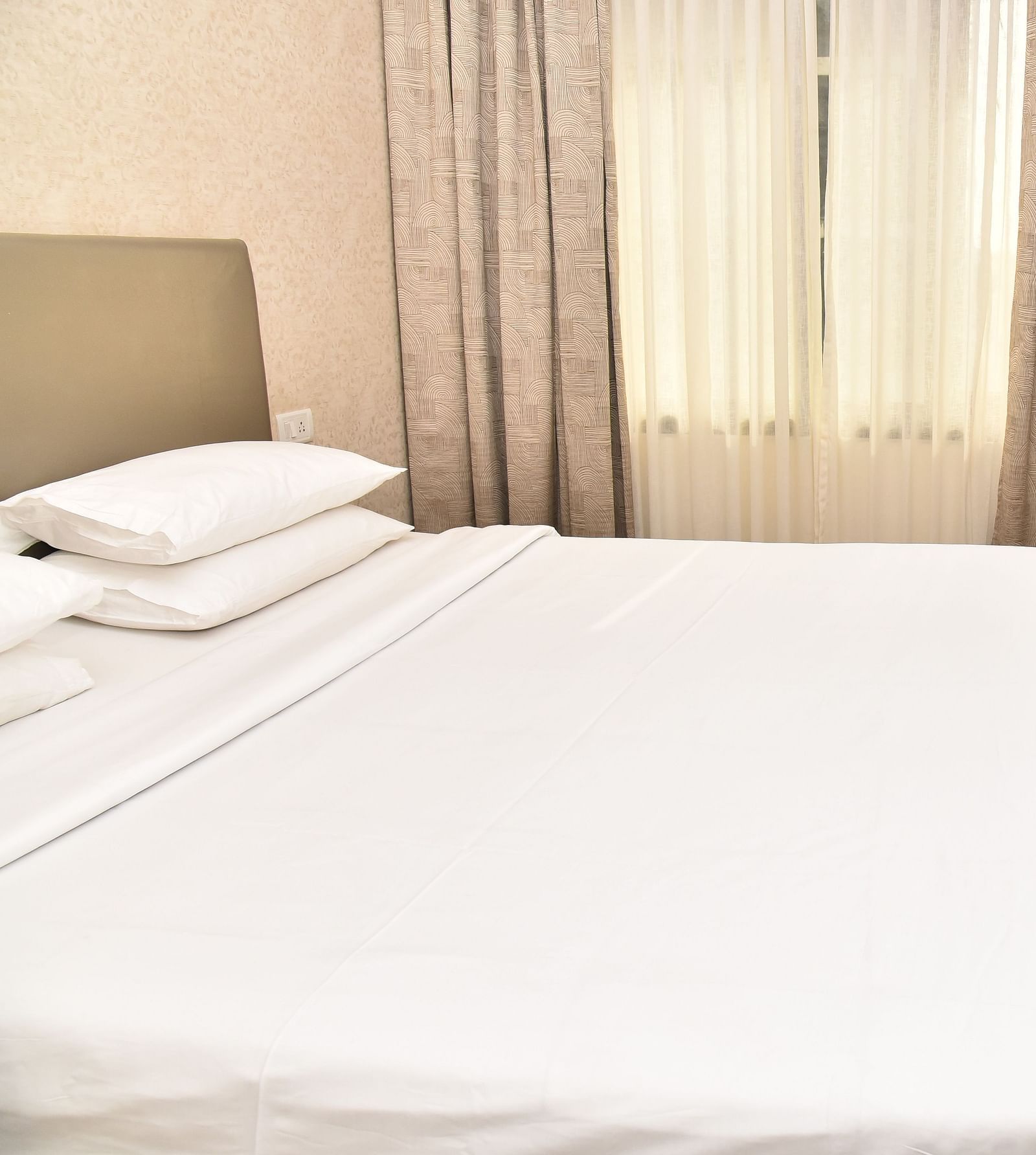 An image of a bedroom in our suite in Kanchipuram, with a large bed positioned in front of a wall-mounted television - Regency Kanchipuram by GRT Hotels