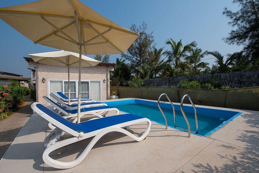 Swimming poolside view with pool loungers and umbrellas