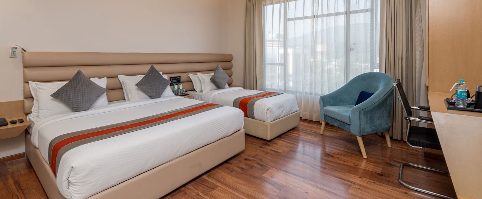 An image featuring a room with two beds, two chairs, a work desk and a window - DLS Hotel Arihant, Haridwar