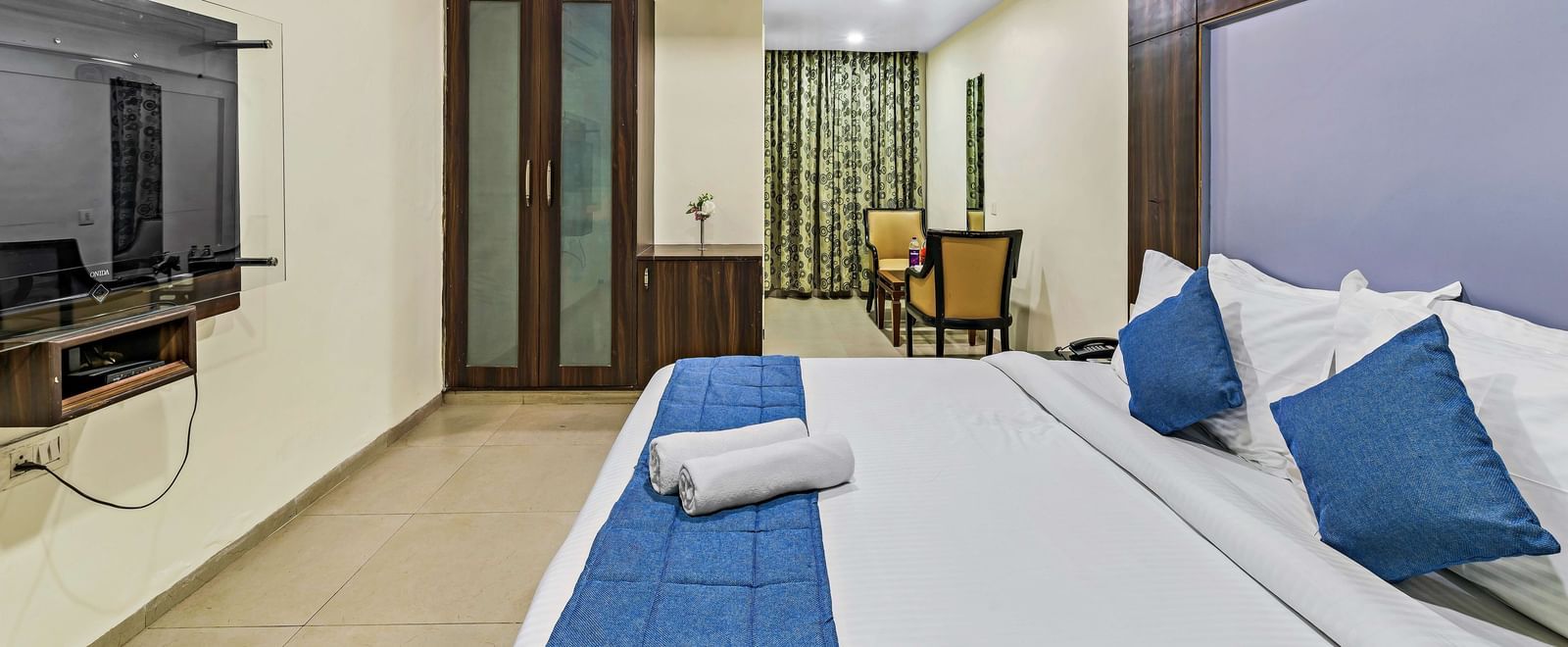 Executive room in Krushnai Resort featuring a double bed with white lnen and blue runner.