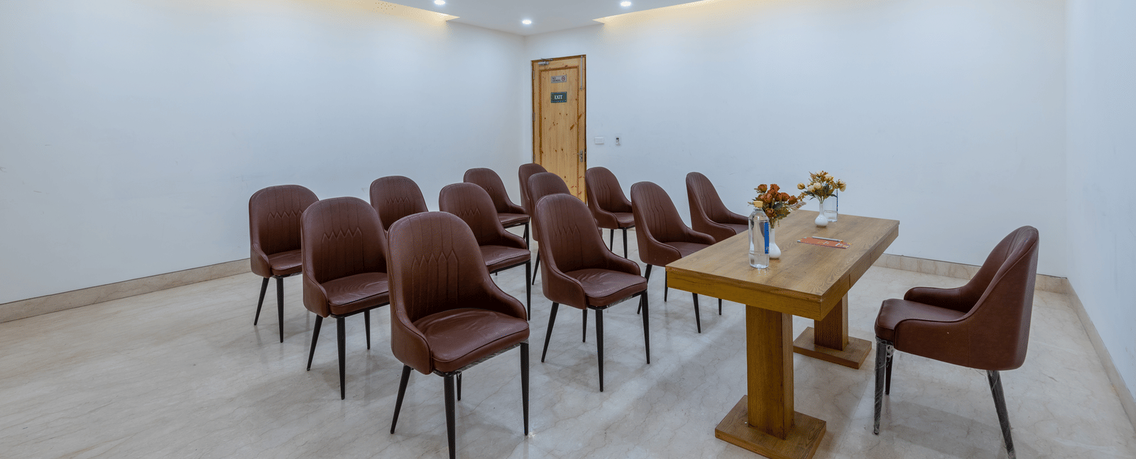 Front view of a conference room with a table placed between a chair and multiple chairs at DLS The Classio