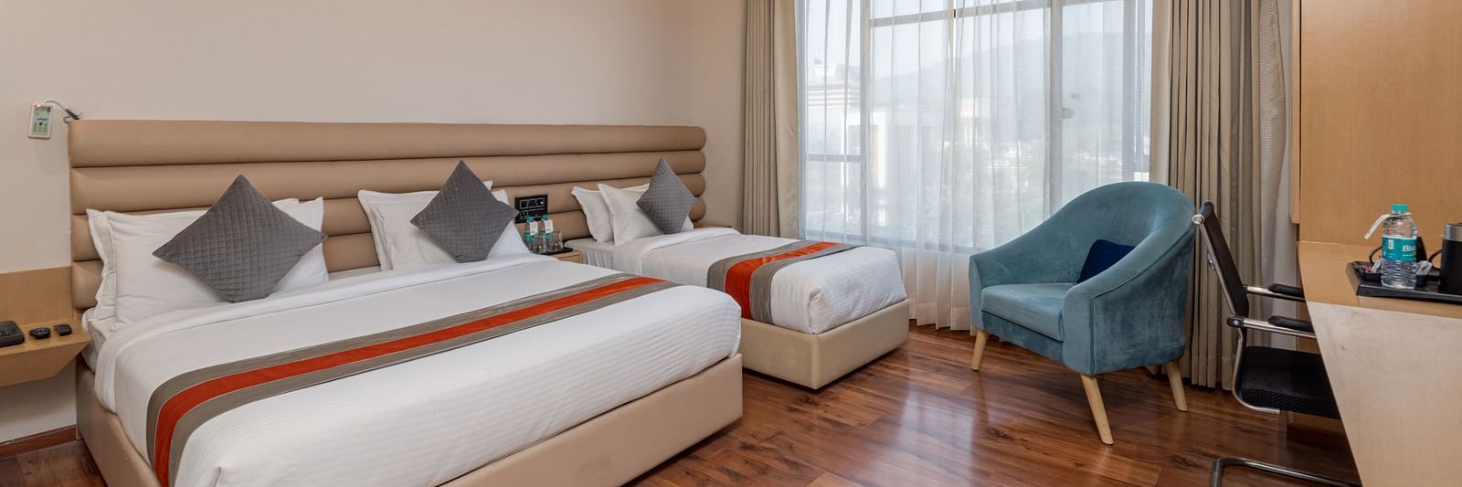 An image featuring a room with two beds, two chairs, a work desk and a window - DLS Hotel Arihant, Haridwar