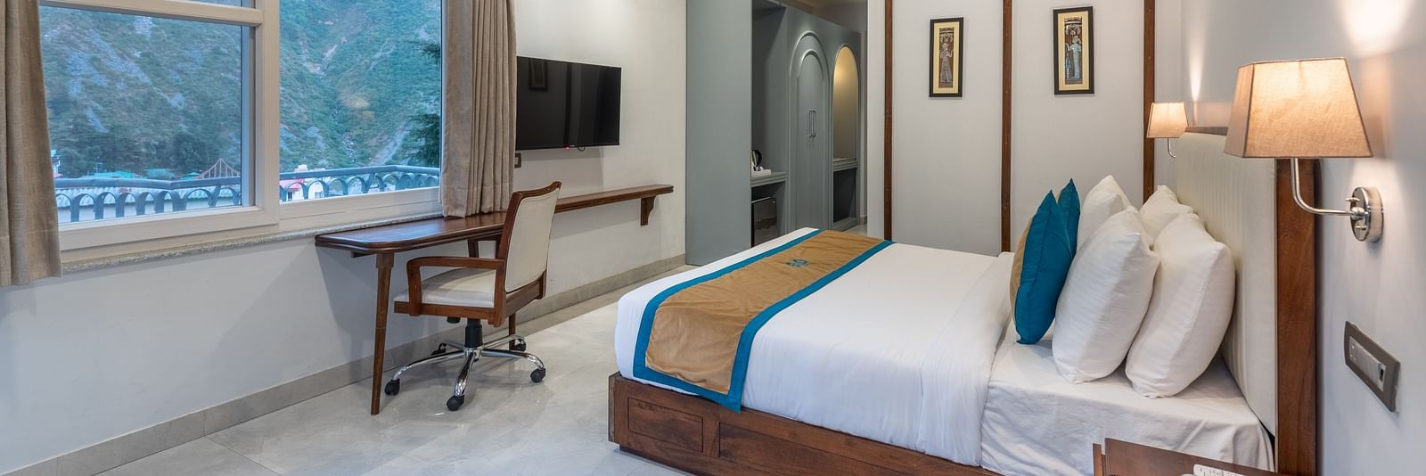 Spring Suite at DLS Spring Valley Resort Dharamshala featuring a kind bed, work desk and chair and ambient lighting from the window