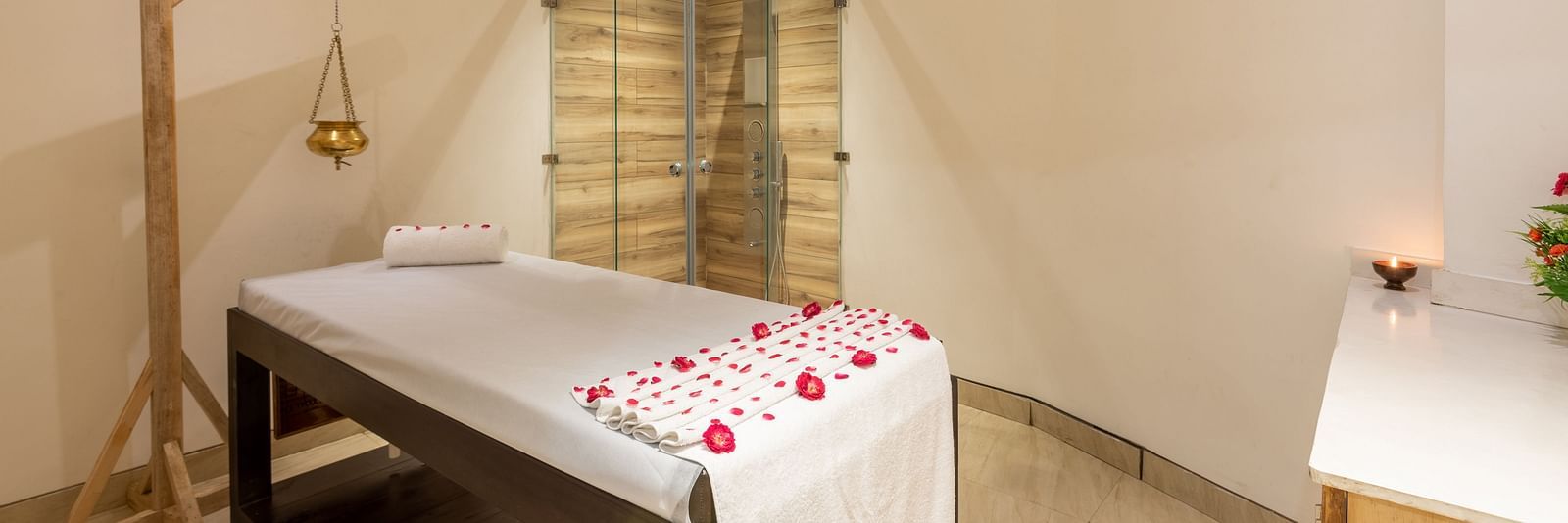 side view of spa with a bed decorated with rose petals and a Shirodhara vessel hanging from a stand at DLS The Classio