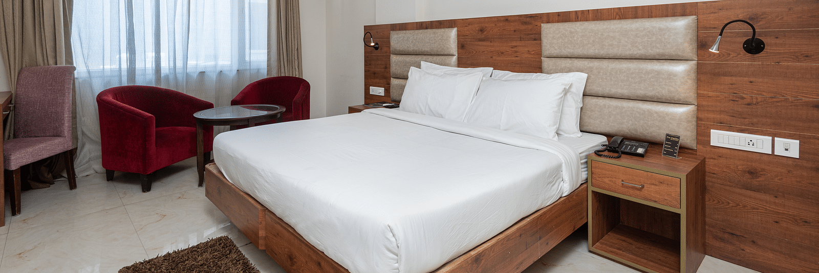 Premium room with a king size bed featuring a stylish headboard, and a window adorned with a soft sheer curtain at DLS The Classio
