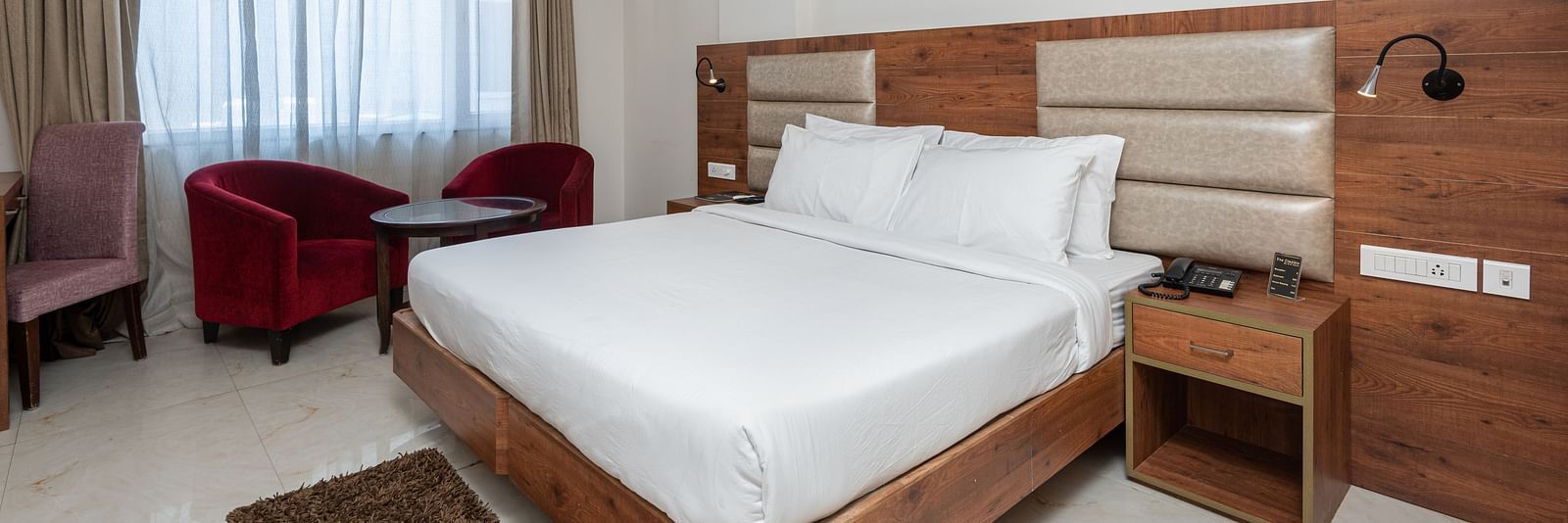  Premium room with a king size bed featuring a stylish headboard, and a window adorned with a soft sheer curtain at DLS The Classio