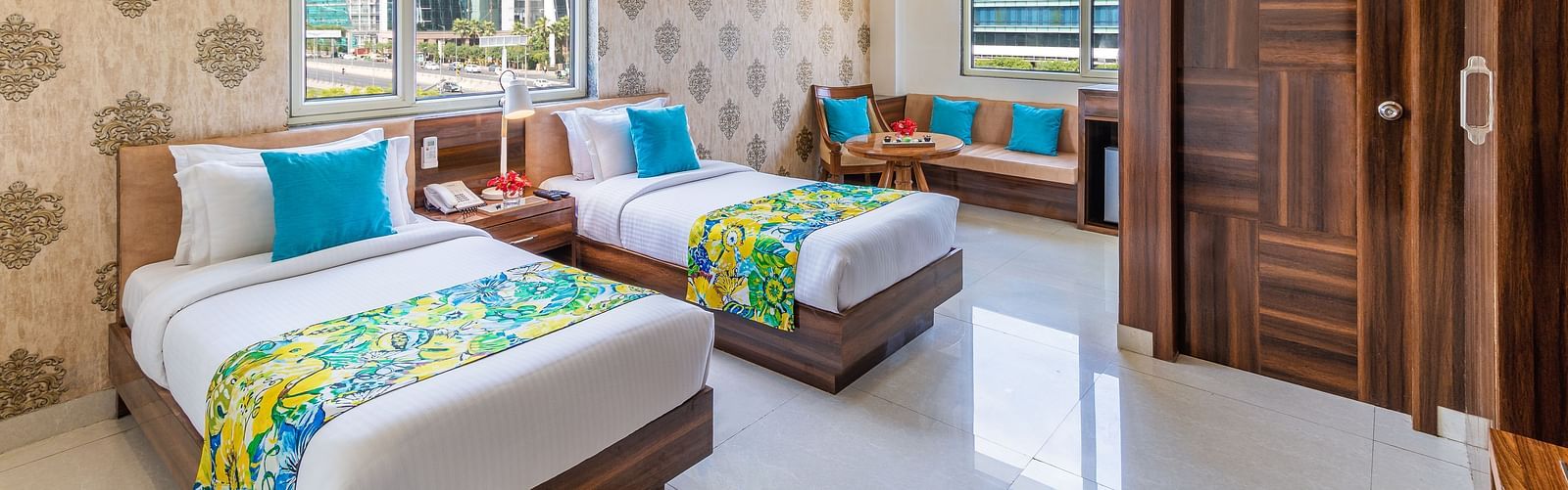 side view image of Super Deluxe Twin Room featuring twin beds, sofa, window and a TV | Inde Hotel Cyber City