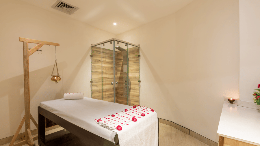 side view of spa with a bed decorated with rose petals and a Shirodhara vessel hanging from a stand at DLS The Classio