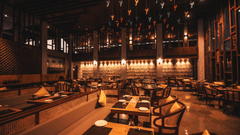 Double-height restaurant at Symphony Oceanus Bay Beach Resort & Spa with cane chairs, banquette seating, and colourful bird ornaments hanging from the ceiling.