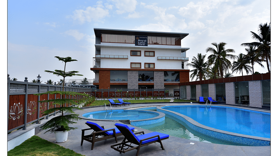 a grand swimming pool in front of resort facade with sunbeds in front and blue sky as the backdrop - Royal Lotus View Resotel