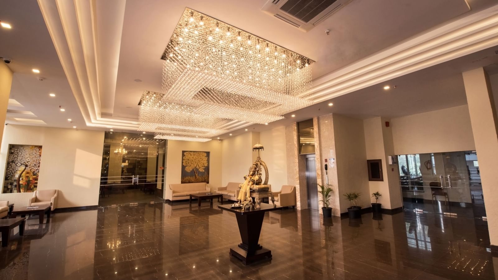 A lobby at Le ROI Digha Hotel, West Bengal featuring a spacious area with sofa sets in each corner and an idol of Lord Ganesha at the centre.