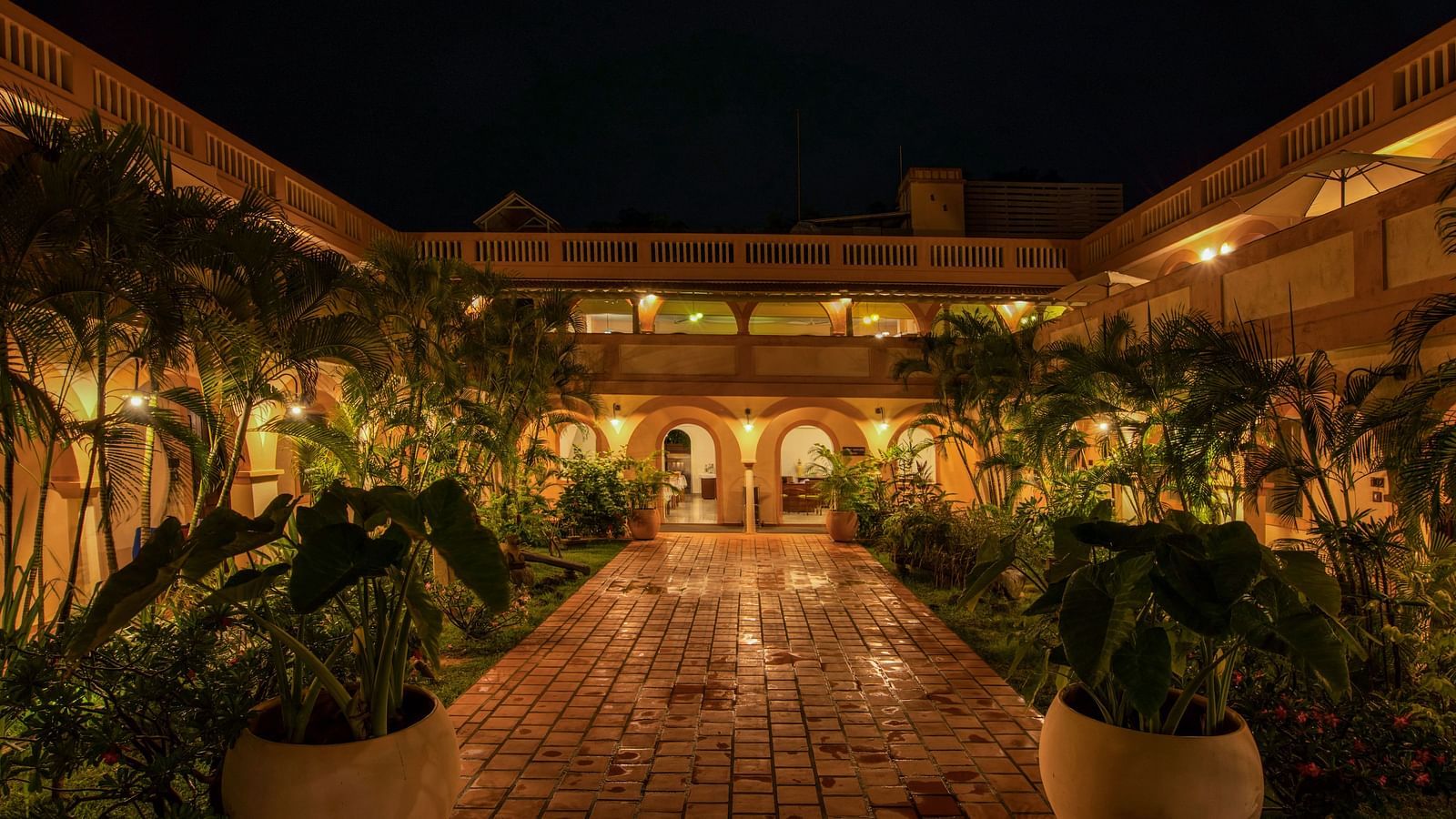 Resort corridor during night time with plants and lights.