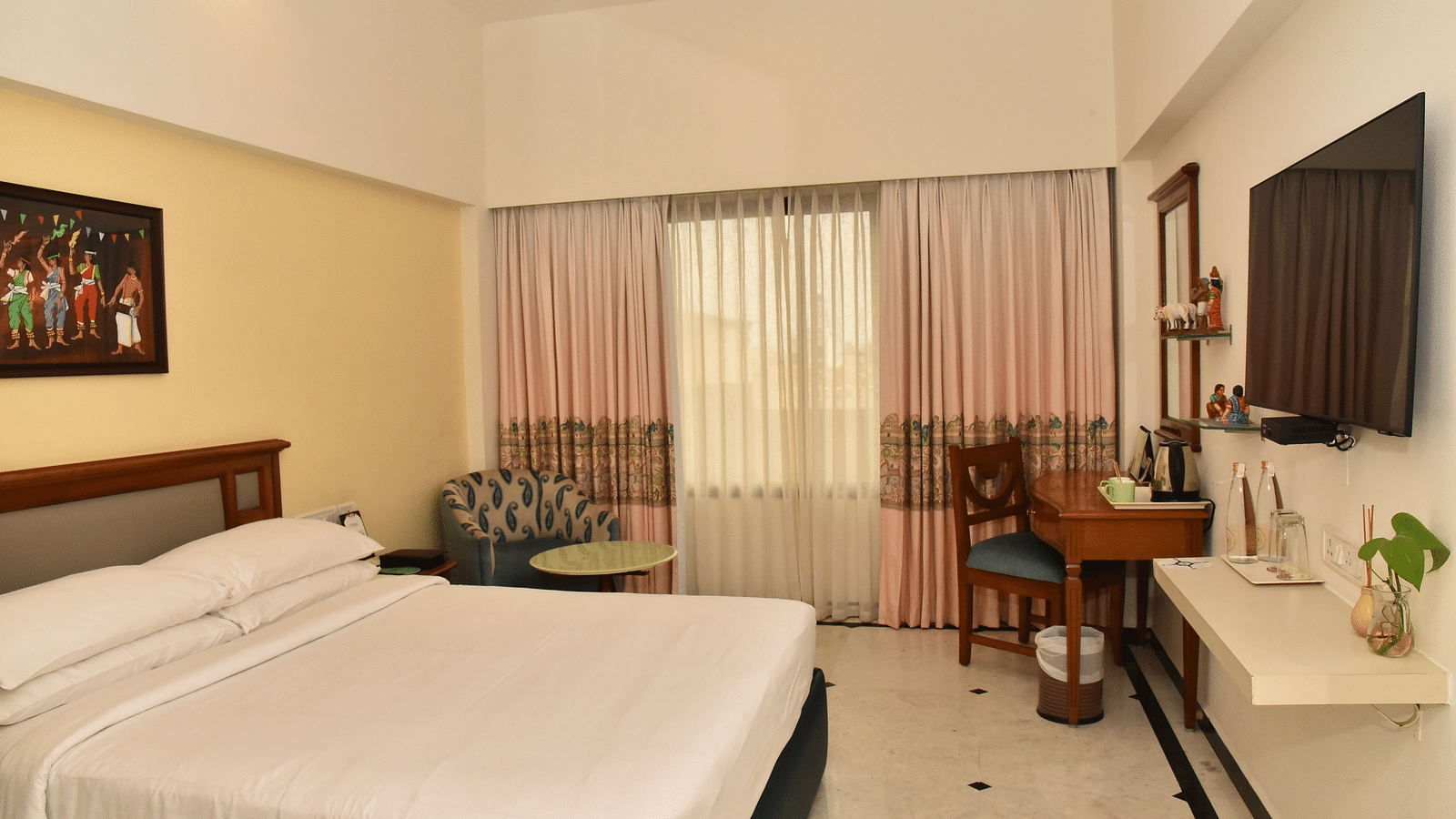 An image of our Deluxe Room featuring a large bed positioned in front of a wall-mounted television - Regency Kanchipuram by GRT Hotels