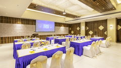 Conference-style banquet setup at the Golden Tulip, Candolim, Goa, with blue-covered tables facing a large screen.