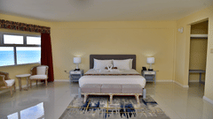 Deluxe Ocean View Room with a king size bed, a long bench, and a seating area next to a window overlooking the ocean at Hotel Grand A View