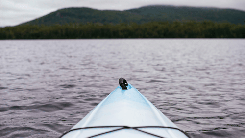 A view from a kayak of the waterbody in front of it and land in the background