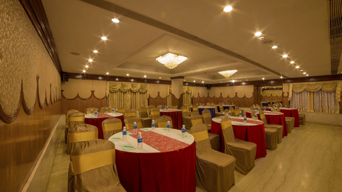 Seating area at Summit conference hall at Raj Park Hotel in Chennai , featuring  chairs, tables, and chandeliers.