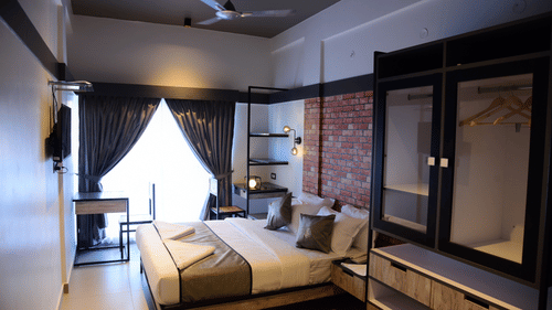 a double bed with a tv opposite it inside one of the rooms - VITS Select Mangalore 