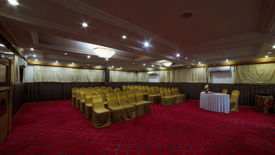 A seating arrangements inside the Senate Banquet hall at the Raj Park Hotel in Chennai, featuring chairs, lights, and a table  witha few chairs.