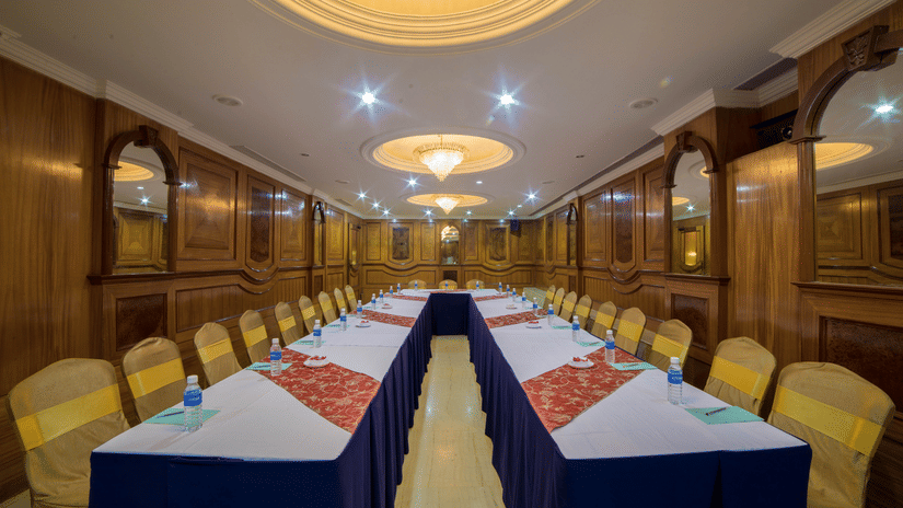 A seating area at a conference hall at Raj Park Hotel in Chennai, with chandeliers, chairs, and tables set up for an event.