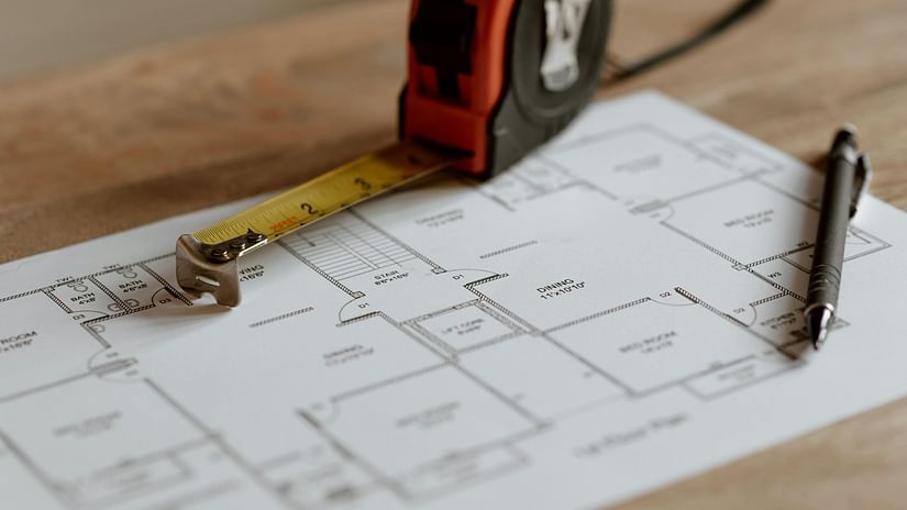 A building layout is spread on paper, with a measuring tape and pen placed on top, ready for use.