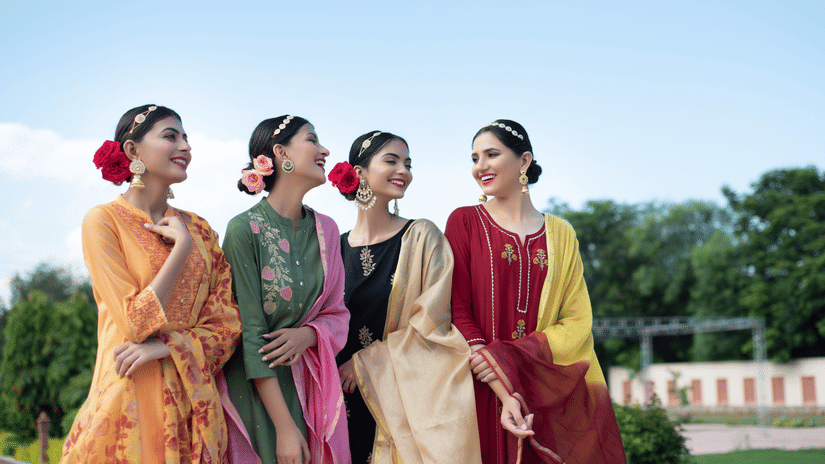Bridesmaids in colourful traditional outfits enjoying an outdoor wedding celebration.