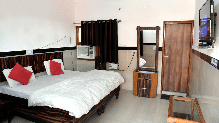 Deluxe AC Room at Hotel Goverdhan at Agra featuring a double size bed, an air conditioner, a dressing table, and a flat TV screen.
