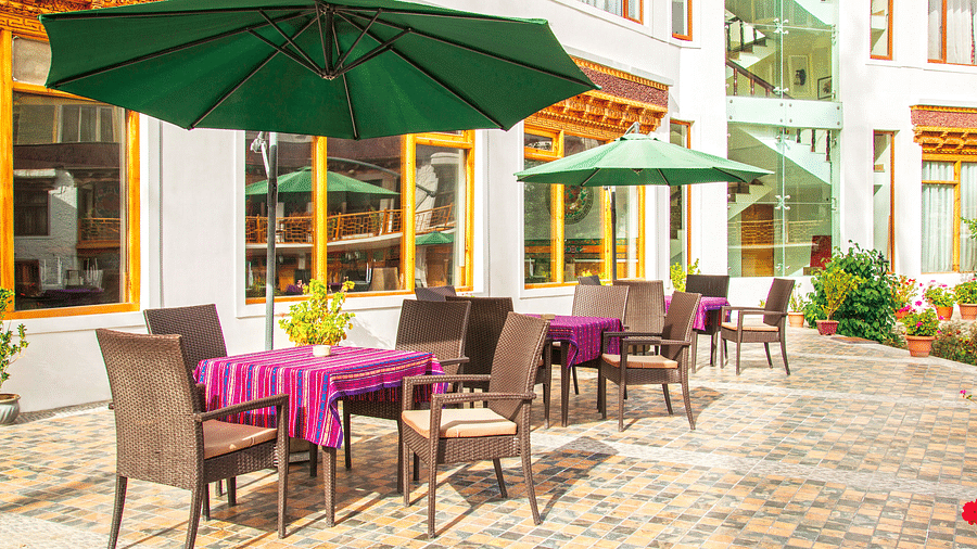 An outdoor seating area at Hotel Singge Palace, featuring tables, chairs, and umbrellas.