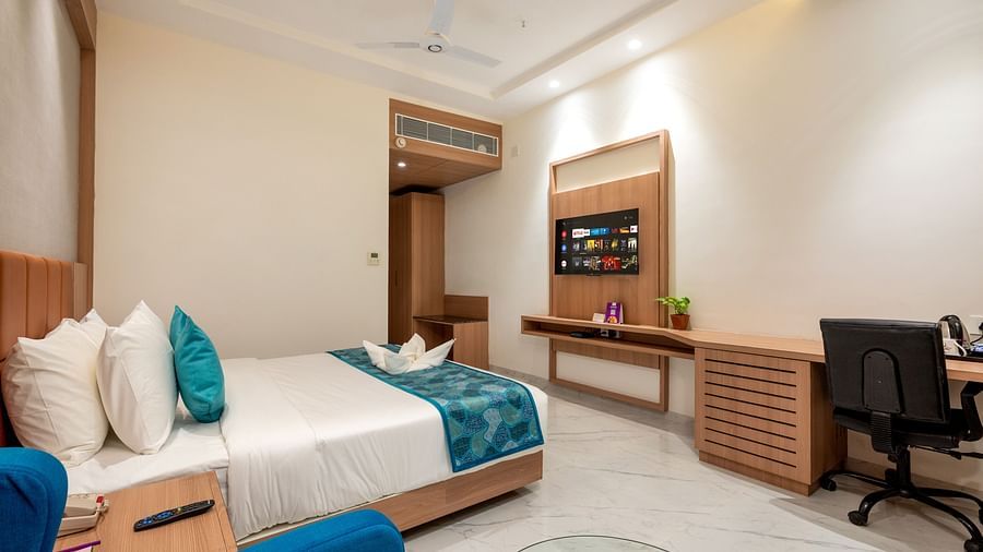 a double bed with blue runner inside one of the Rooms - The Orchid Hotel, Jamnagar