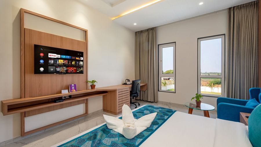 a double bed with blue runner inside one of the Rooms - The Orchid Hotel, Jamnagar