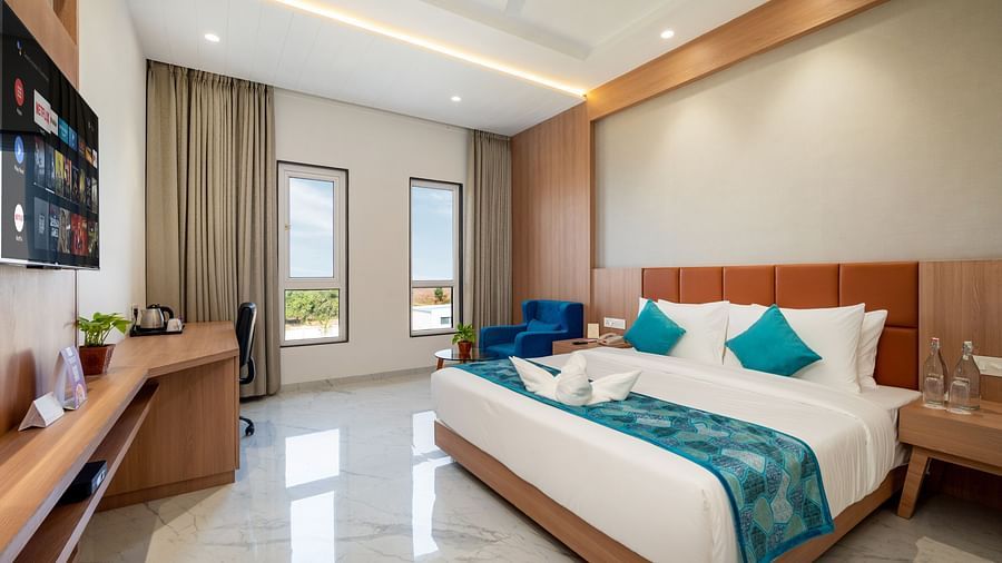 a double bed with blue runner inside one of the Rooms - The Orchid Hotel, Jamnagar