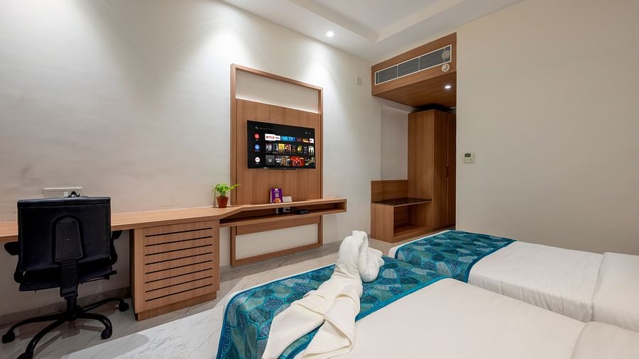 twin beds with blue runner inside one of the Rooms - The Orchid Hotel, Jamnagar