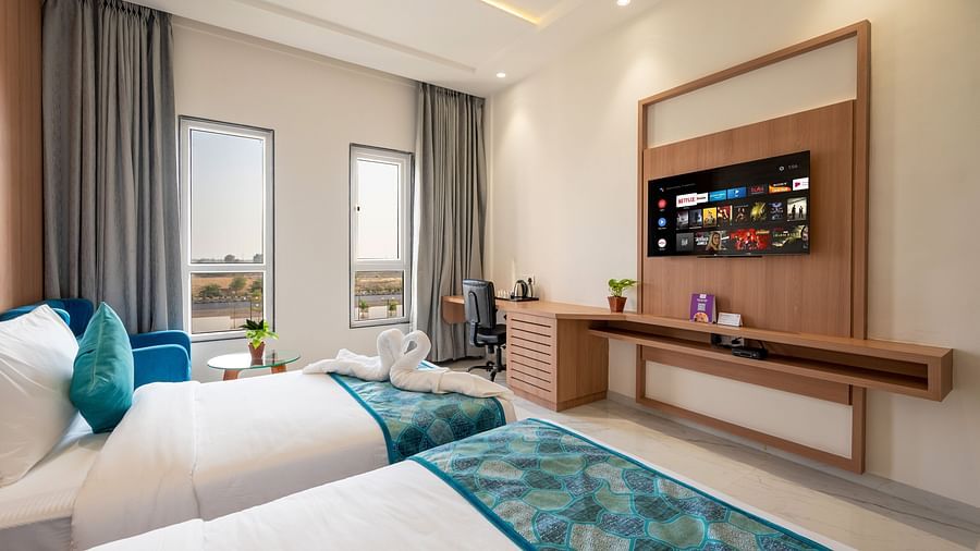 twin beds with blue runner inside one of the Rooms - The Orchid Hotel, Jamnagar