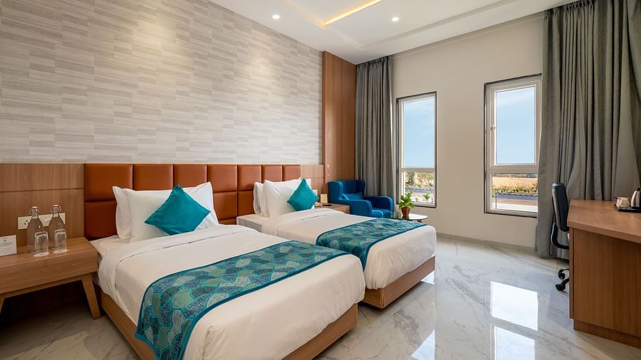 twin beds with blue runner inside one of the Rooms - The Orchid Hotel, Jamnagar